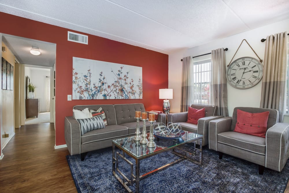 Comfy living room with large blue area rug, grey couch, and armchairs at Briarcrest at Winter Haven in Winter Haven, Florida