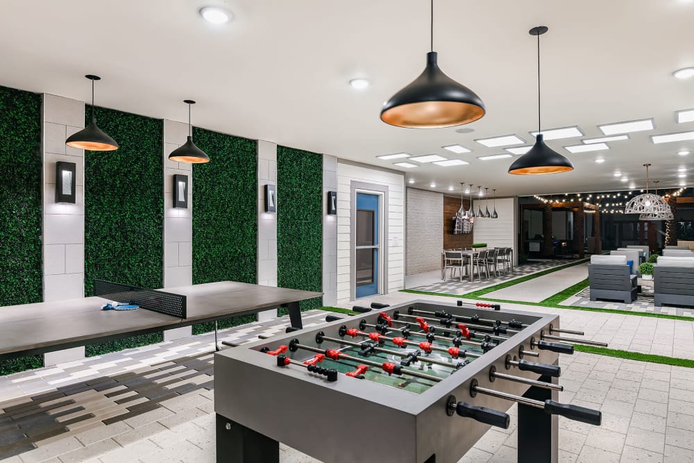 Resident game room with foosball table and hanging light fixtures at Soba Apartments in Jacksonville, Florida
