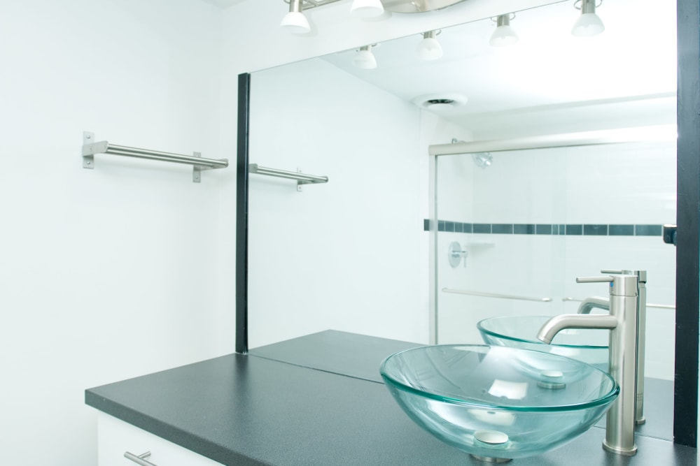 Bathroom with glass vessel sink and glass shower doors at 3Fifty8 in Lexington, Kentucky