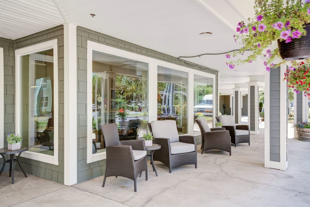 Outdoor seating with hanging flower plants at Timber Pointe Senior Living in Springfield, Oregon. 