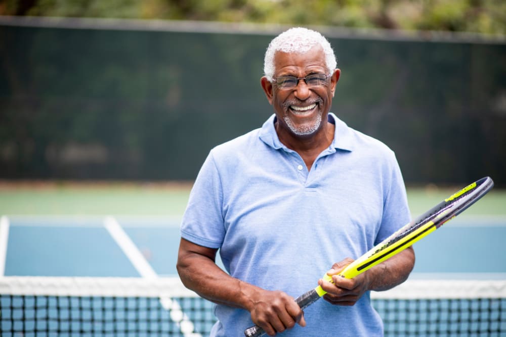 Resident smiling and holding tennis racket at Haven at Lewisville Lake in Lewisville, Texas.