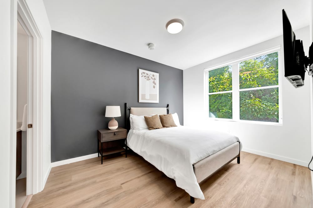 Cozy bedroom with large window for ample natural light at The Robert in Portland, Oregon