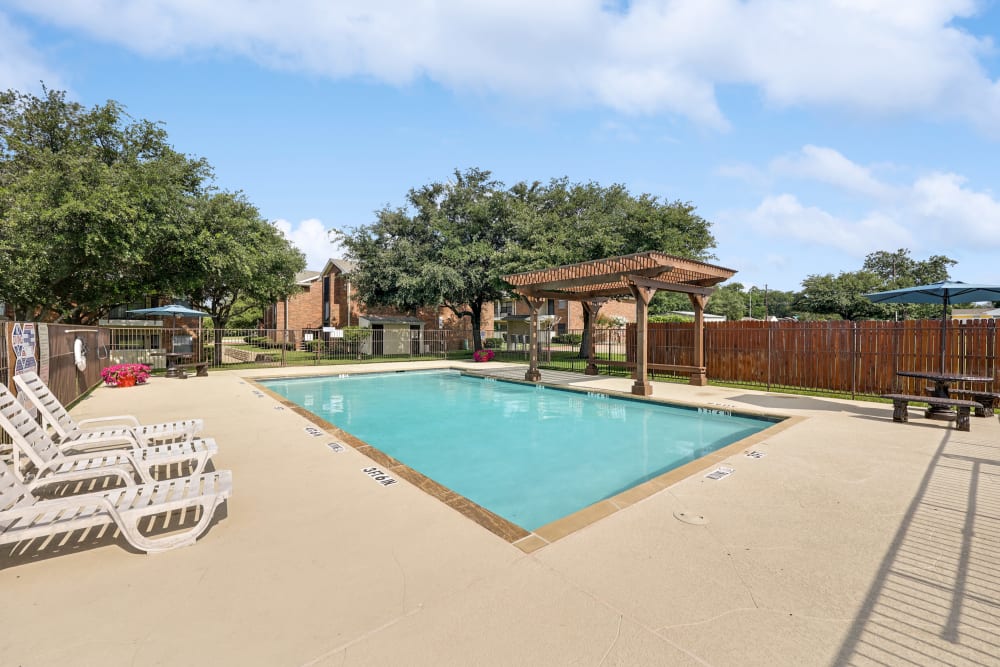 Sparkling swimming pool with poolside pergola and patio table at Summit Point Apartments in Mesquite, Texas