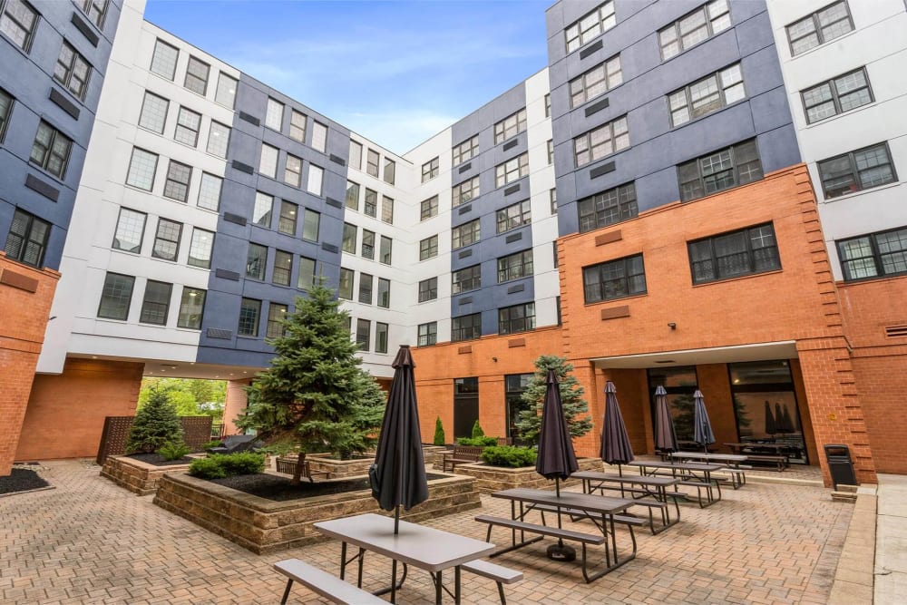 Courtyard with row of picnic tables with umbrellas at Parc at Lyndhurst in Lyndhurst, New Jersey