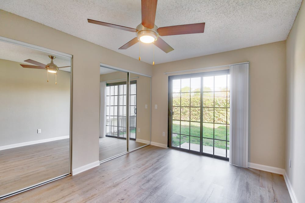 Empty bedroom with hardwood floors and a sliding glass door. 