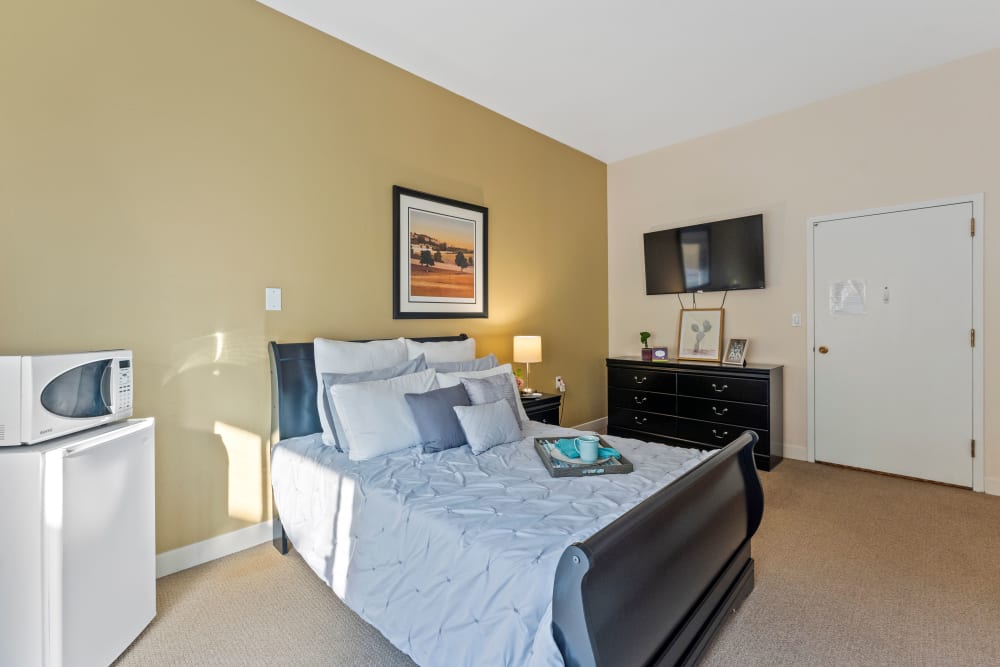 Resident bedroom with dresser and large tv at Pacifica Senior Living Burlingame in Burlingame, California