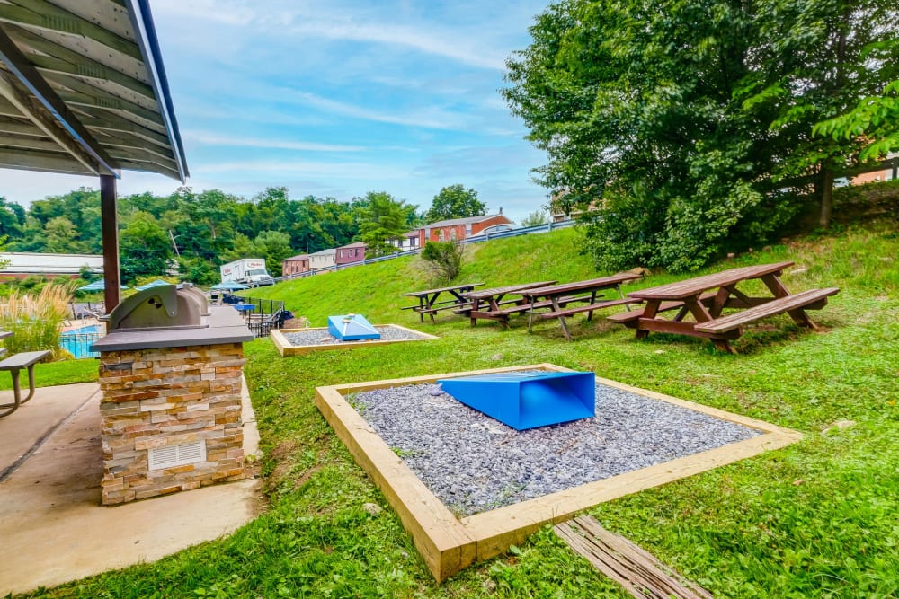 Outdoor grilling area with picnic table and cornhole set at Park Place of South Park in South Park, Pennsylvania