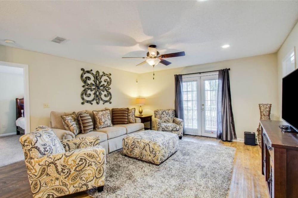 A furnished apartment living room with doors to the patio at The Gables in Ridgeland, Mississippi