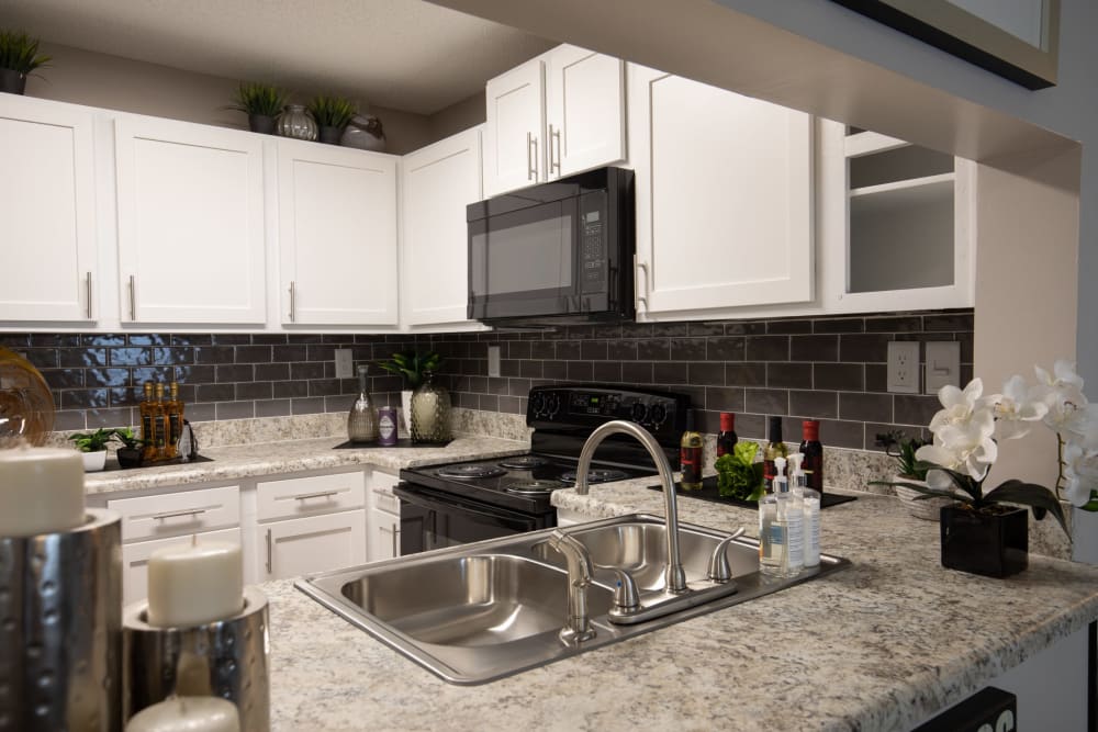 White cabinets and black appliances in an apartment kitchen at Renaissance at Galleria in Hoover, Alabama