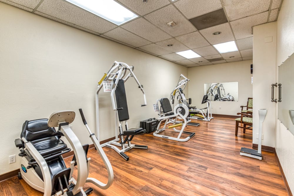 Exercise room with multiple workout machines at Pacifica Senior Living Menifee in Sun City, California