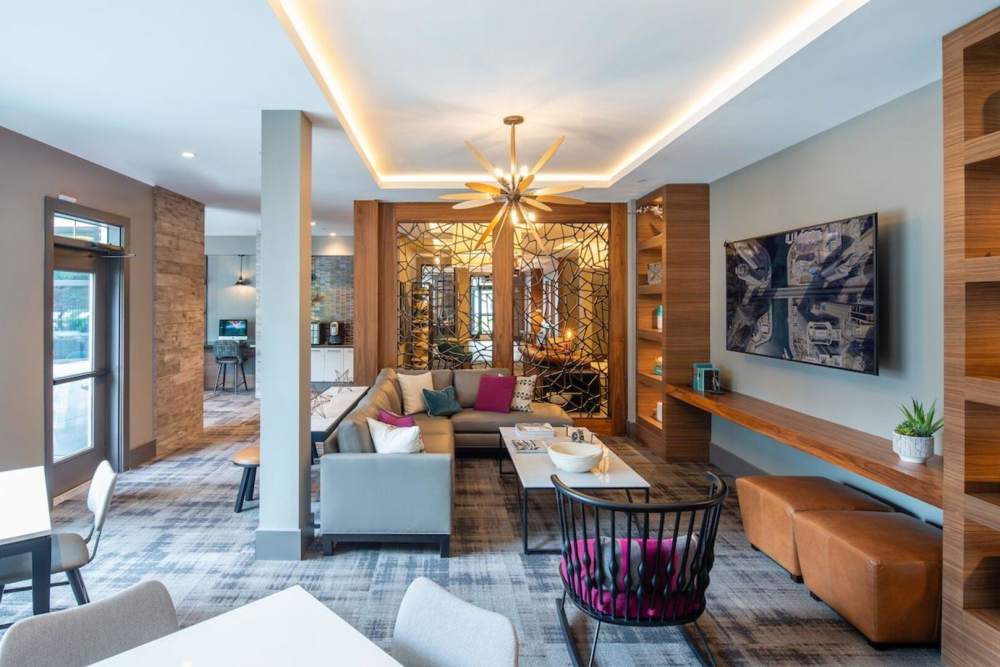 Community waiting hall with chairs, tv and coffee table at The Elms at Century in Germantown, Maryland