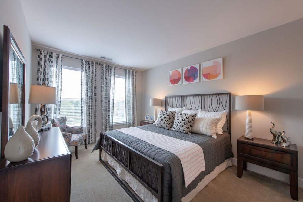 Cozy bedroom with large windows and night stand at The Elms at Century in Germantown, Maryland