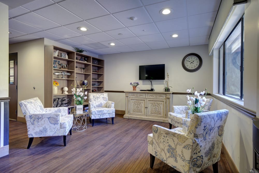 Resident lounge area with large bookcases and television at Pacifica Senior Living Rancho Peñasquitos in San Diego, California