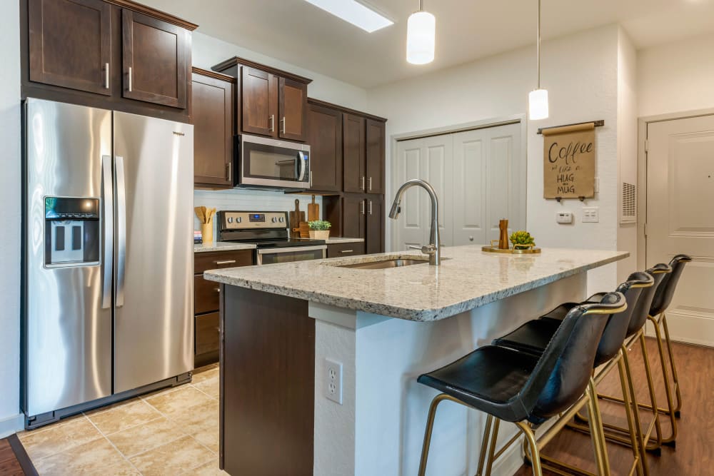 Modern kitchen with stainless steel appliances and breakfast bar at Regatta at Universal Apartments in Orlando, Florida 