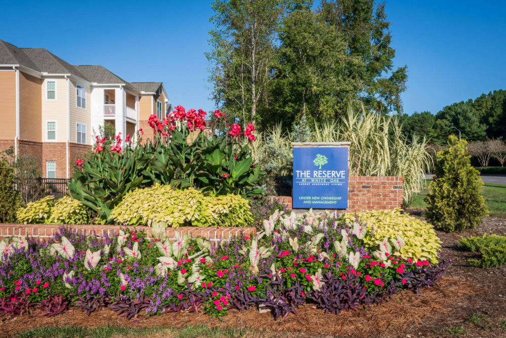 Exterior welcoming sign surrounded by tons of flowers at The Reserve at White Oak in Garner, North Carolina