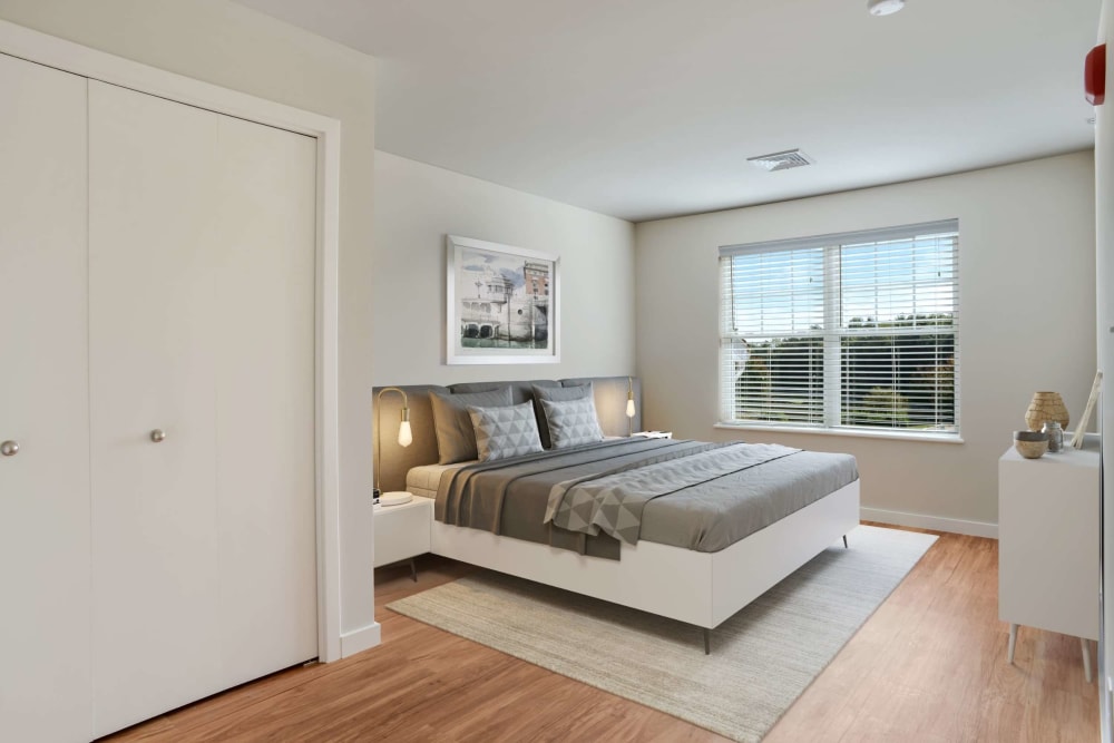 Bedroom with wood style flooring and natural sunlight at Bay Ridge at Nashua Apartments in Nashua, New Hampshire