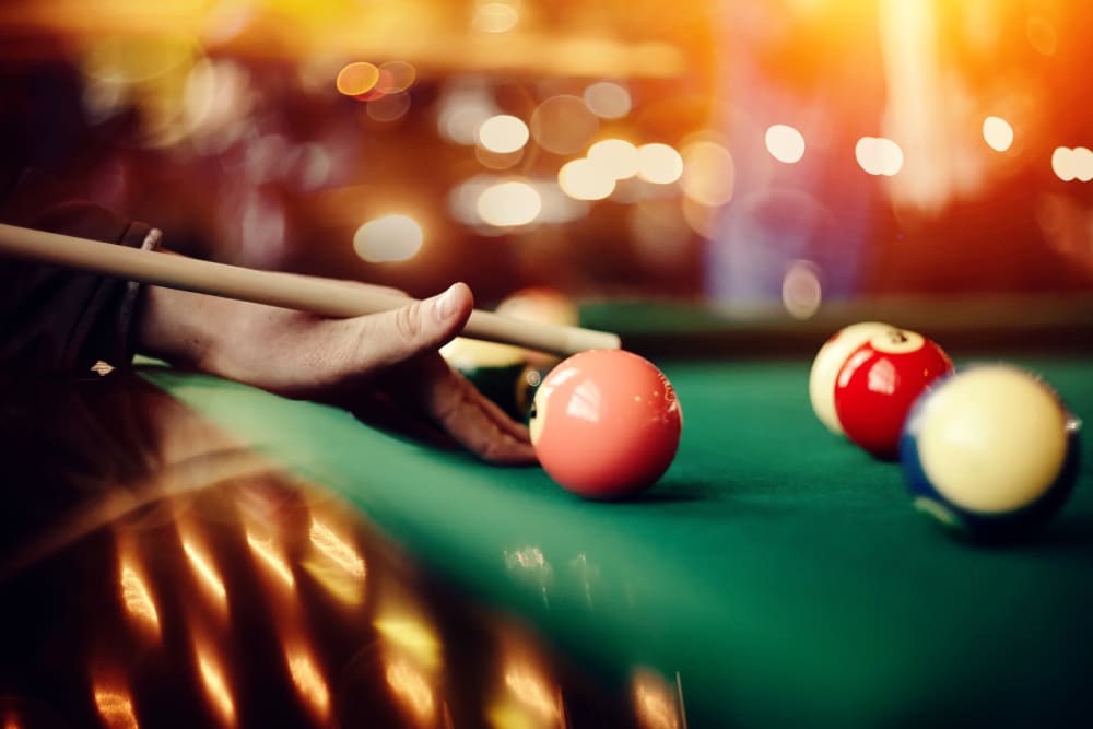 Pool cue and balls on a green pool table at New Shiloh Village Family Apartments in Baltimore, Maryland