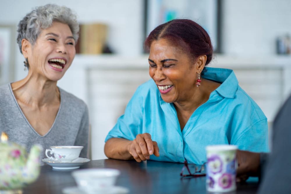Two Senior women laughing and drinking coffee at New Shiloh Village Senior Apartments in Baltimore, Maryland