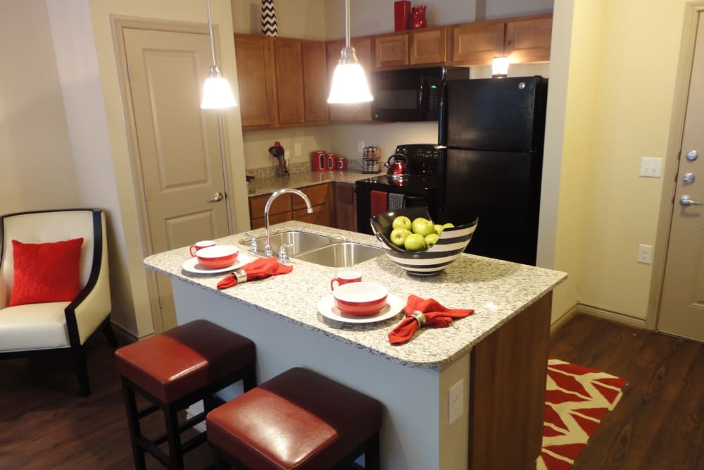 Kitchen with appliances and island seating at Anatole at City View in Lubbock, Texas
