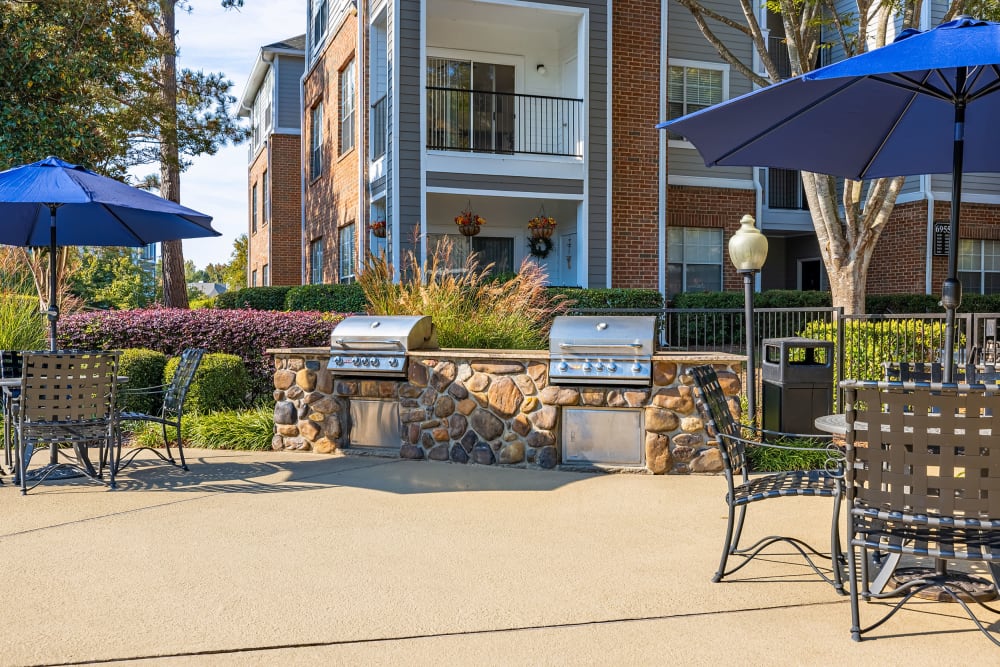 Stone BBQs next to dining tables and chairs with umbrellas at Marquis of Carmel Valley in Charlotte, North Carolina