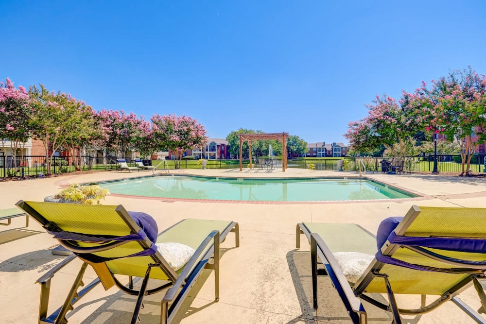 Patio chairs next to the outdoor pool at Champion Lake Apartment Homes in Shreveport, Louisiana