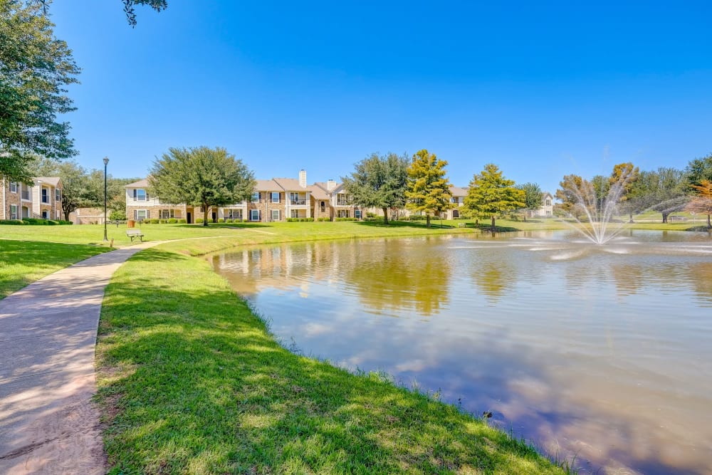 Pond and fountain with walking path at River Walk Apartment Homes in Shreveport, Louisiana