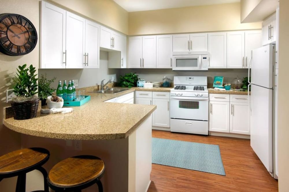 Apartment kitchen with white cabinets and appliances at Artisan at East Village Apartments in Oxnard, California