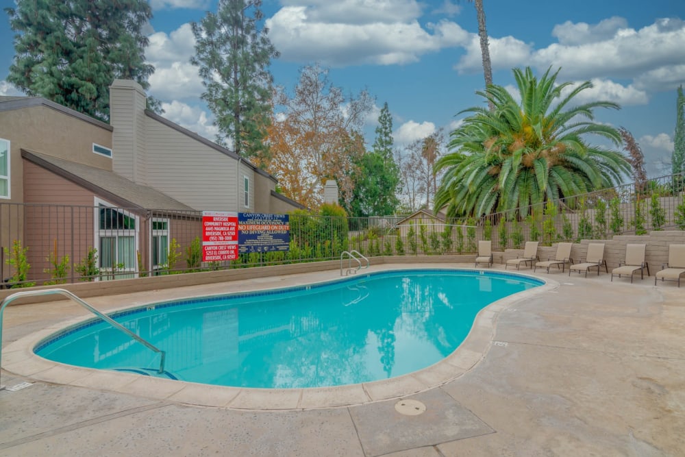 In-ground pool with lounge seating at Canyon Crest Views Apartments in Riverside, California