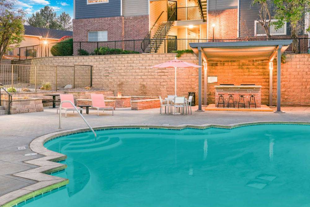 Beautiful resort-style swimming pool with lounge chairs at The Crossings at Bear Creek Apartments in Lakewood, Colorado