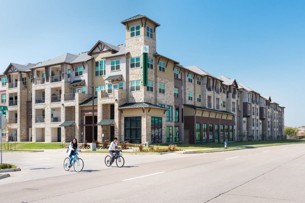 Two residents riding bikes outside the apartments at Discovery Park in Denton, Texas