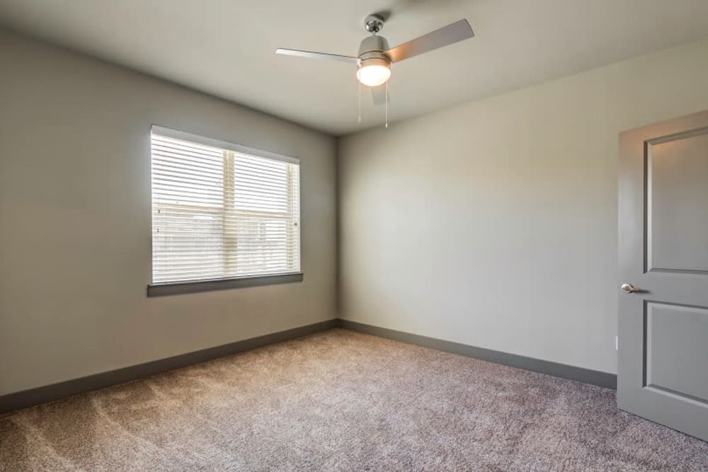 Large carpeted bedroom with ceiling fan at Discovery Park in Denton, Texas