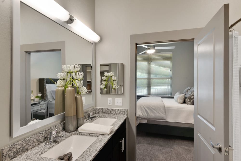 Master bathroom featuring a his-and-her sink and granite countertop at Discovery Park in Denton, Texas