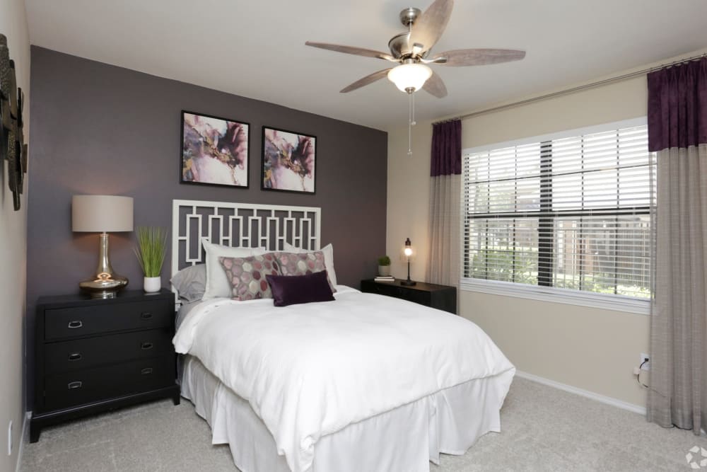 Second bedroom with ceiling fan and large window at The Columns at Westchase in Houston, Texas