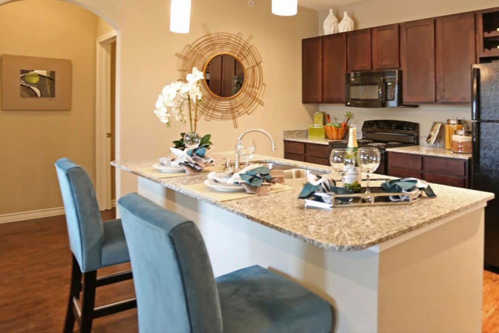 Fully-equipped kitchen with granite counters, island seating, and modern appliances at Latigo at Eagle Pass in Eagle Pass, Texas