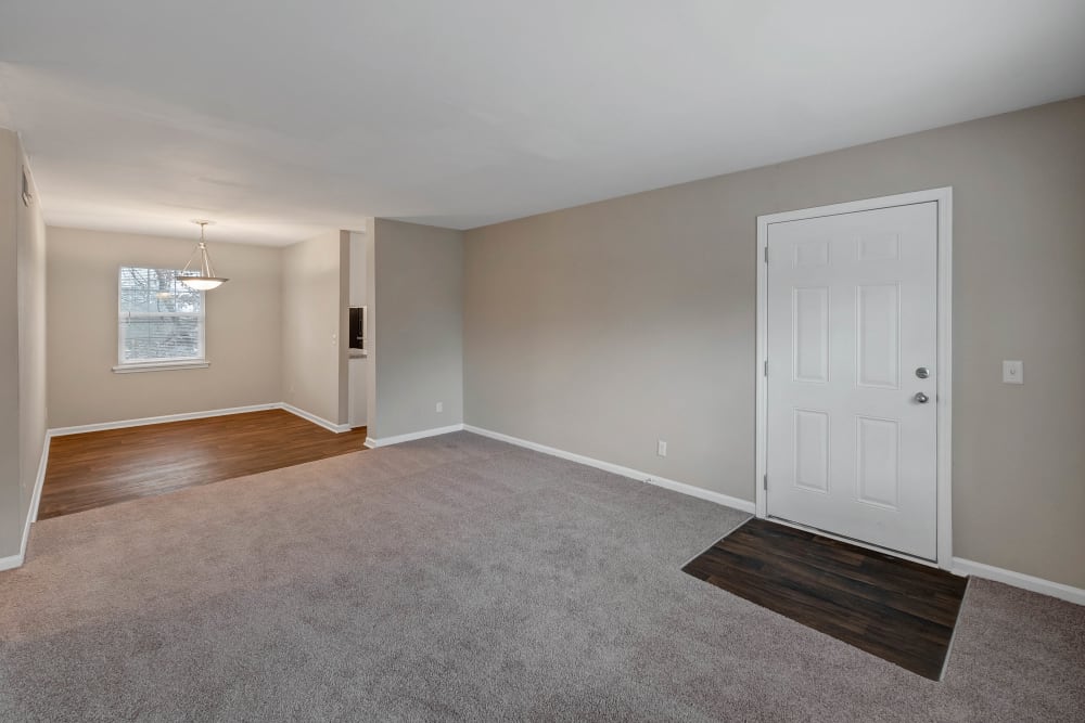 Living room with plush carpet and dining area with hardwood style flooring at Redmond Chase Apartment Homes in Rome, Georgia