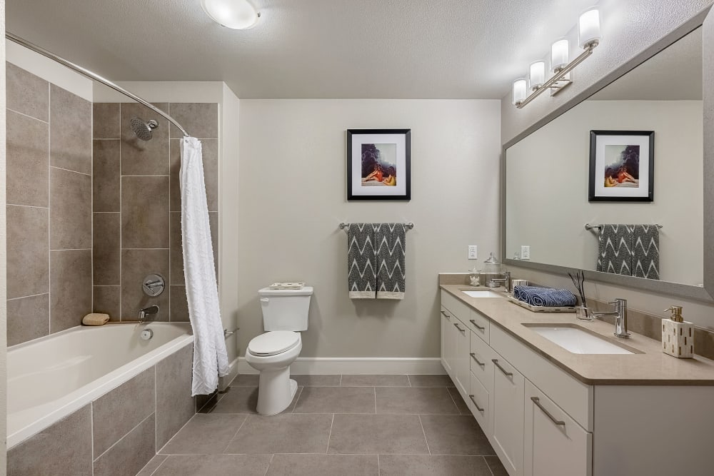 Spa inspired bathroom with white cabinets and tile flooring and shower and tub at Water Marq in Austin, Texas