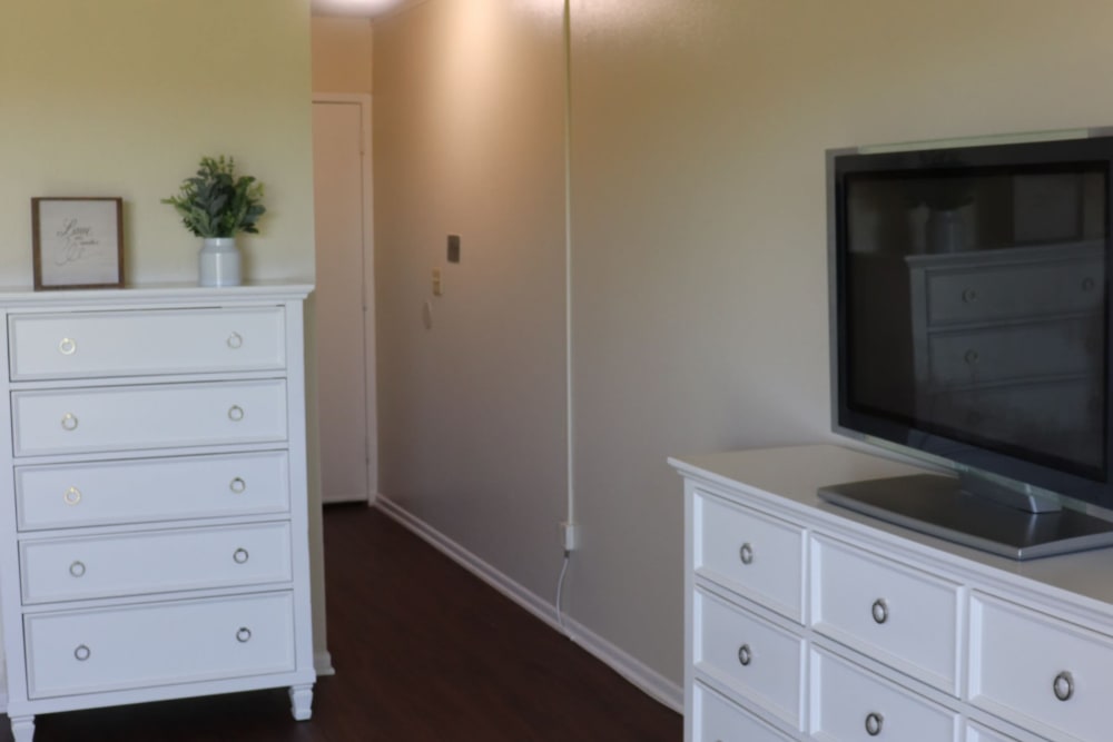 Resident apartment bedroom with 2 dressers and large tv at Sun City Gardens in Sun City, California