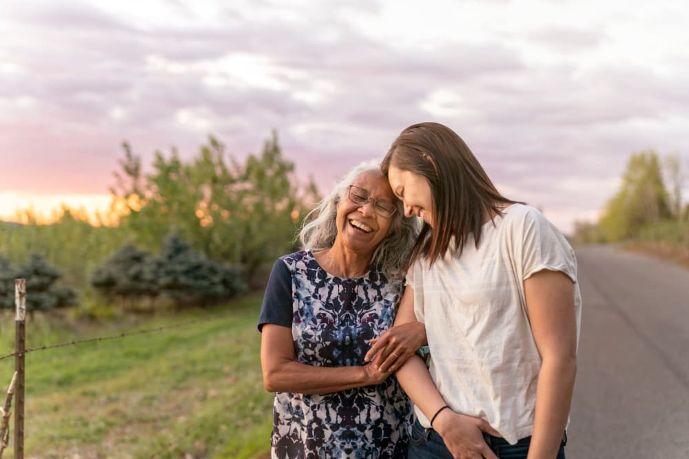 Resident and caregiver smiling together outdoors at The Whitcomb Senior Living Tower in St. Joseph, Michigan