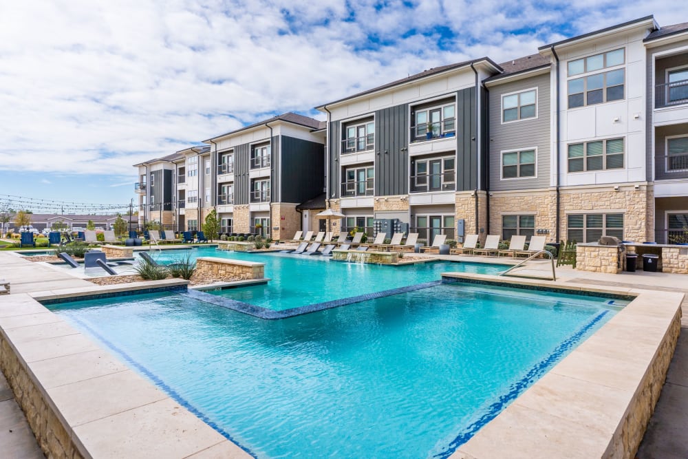 Swimming pool with view of apartments at The Everett at Ally Village in Midland, Texas