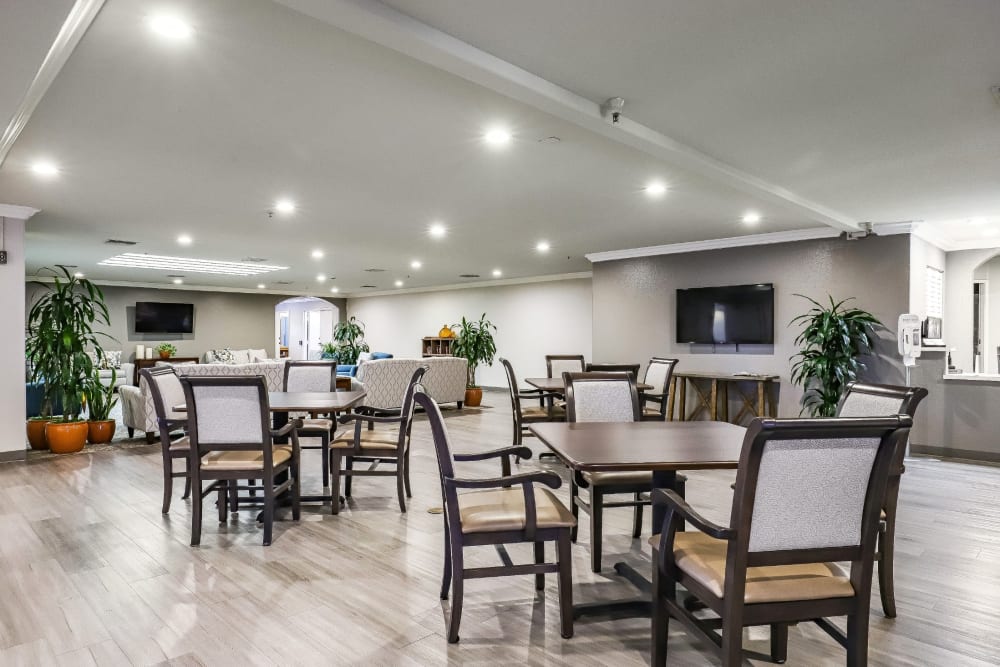 Resident dining area with seating and large wall mounted television at Pacifica Senior Living Poway in Poway, California