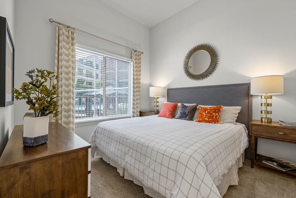 Carpeted bedroom with wood side tables, dresser, and large bed at Marq on Burnet in Austin, Texas