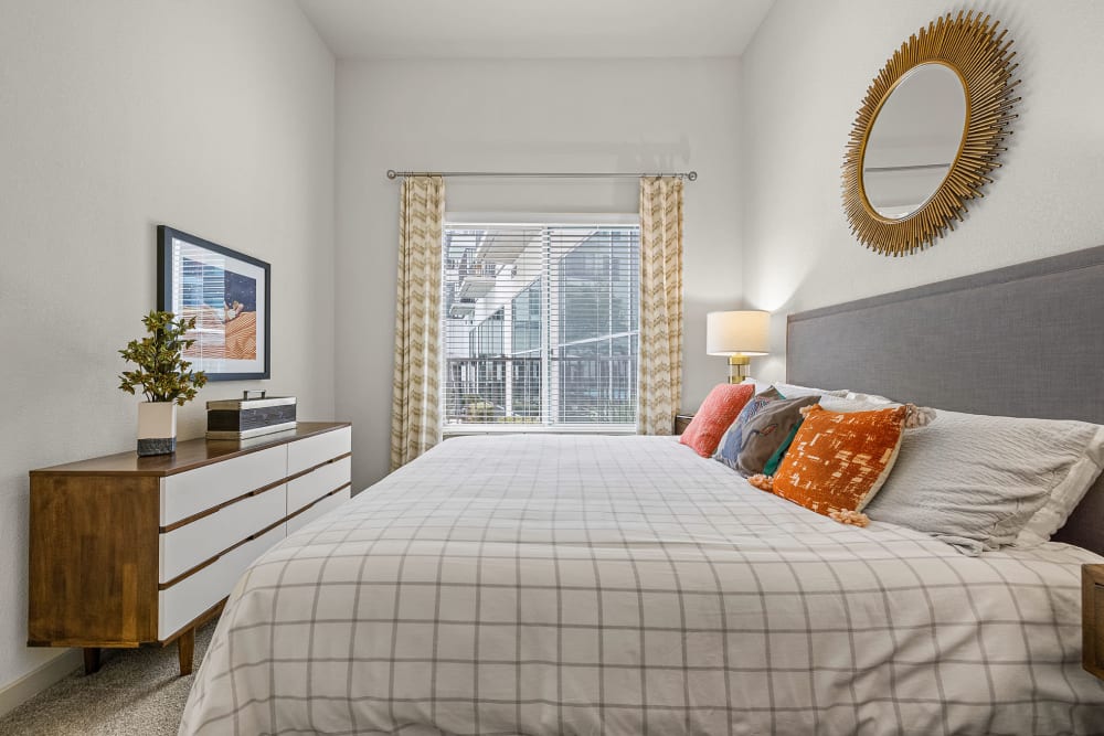 Carpeted bedroom with wood side tables, dresser, and large bed at Marq on Burnet in Austin, Texas
