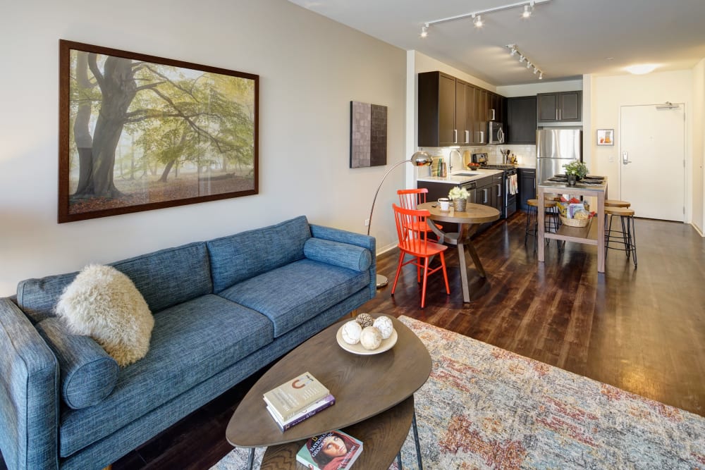 Living room with large area rug and blue couch at Courthouse Square Apartments in Wheaton, Illinois