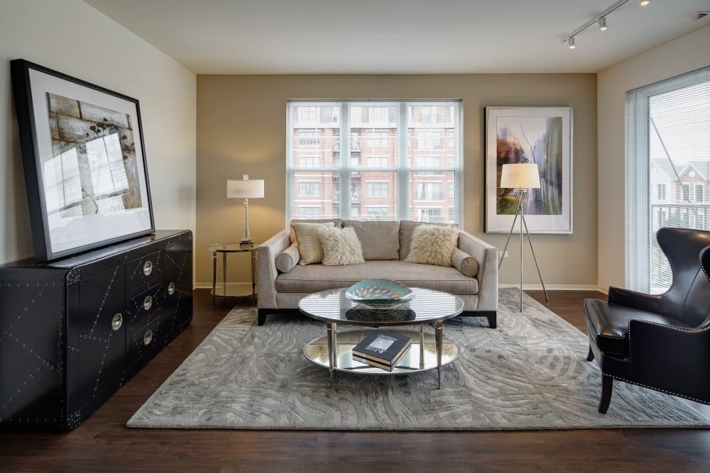 Spacious living room with seating, large area rug, and coffee table at Courthouse Square Apartments in Wheaton, Illinois