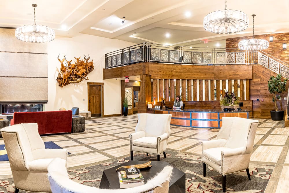 Reception desk and spacious seated lounge with chandeliers at Touchmark at Pilot Butte in Bend, Oregon