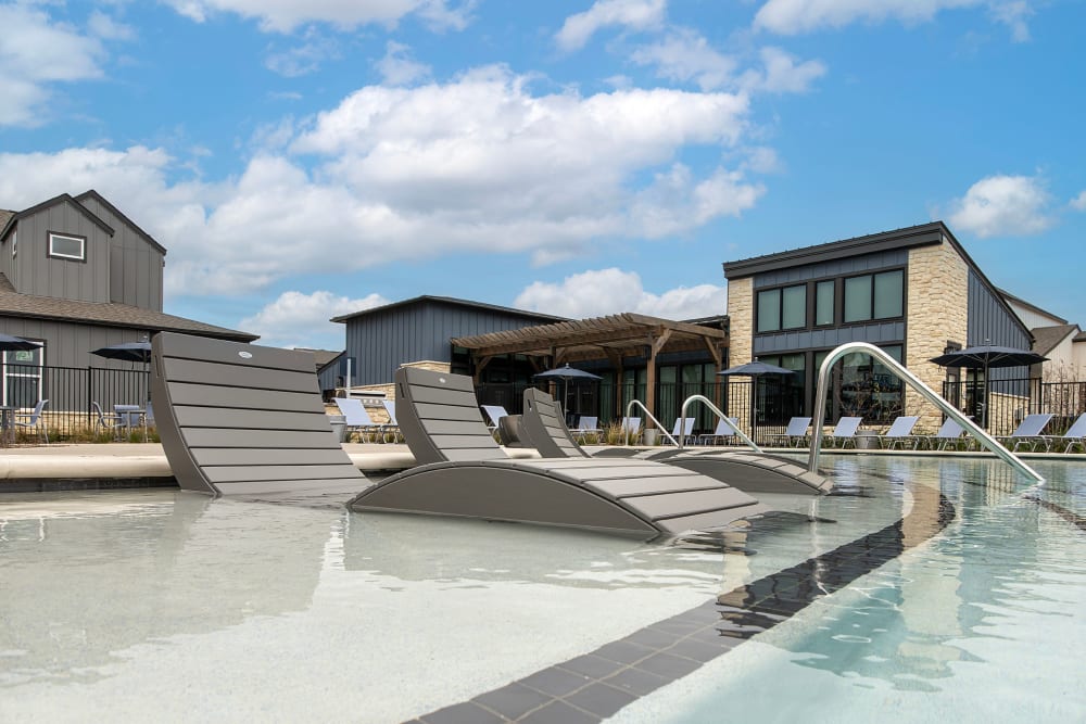 Resort-infused pool with tanning deck and pool loungers at parcHAUS AT CELINA PARKWAY in Celina, Texas