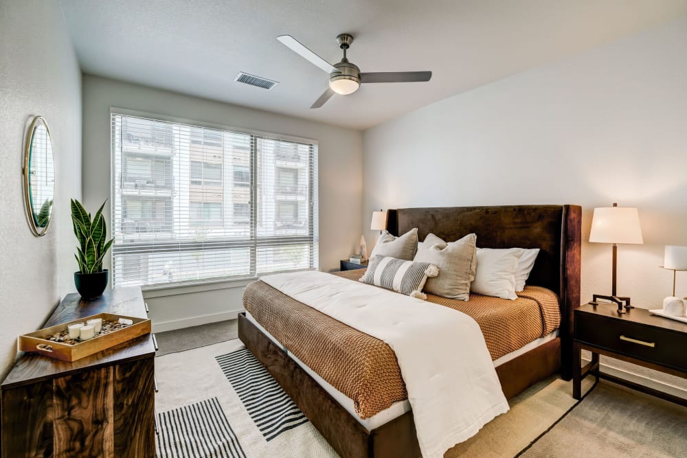 Model bedroom with ceiling fan and large window at Vue West Apartment Homes in Denver, Colorado