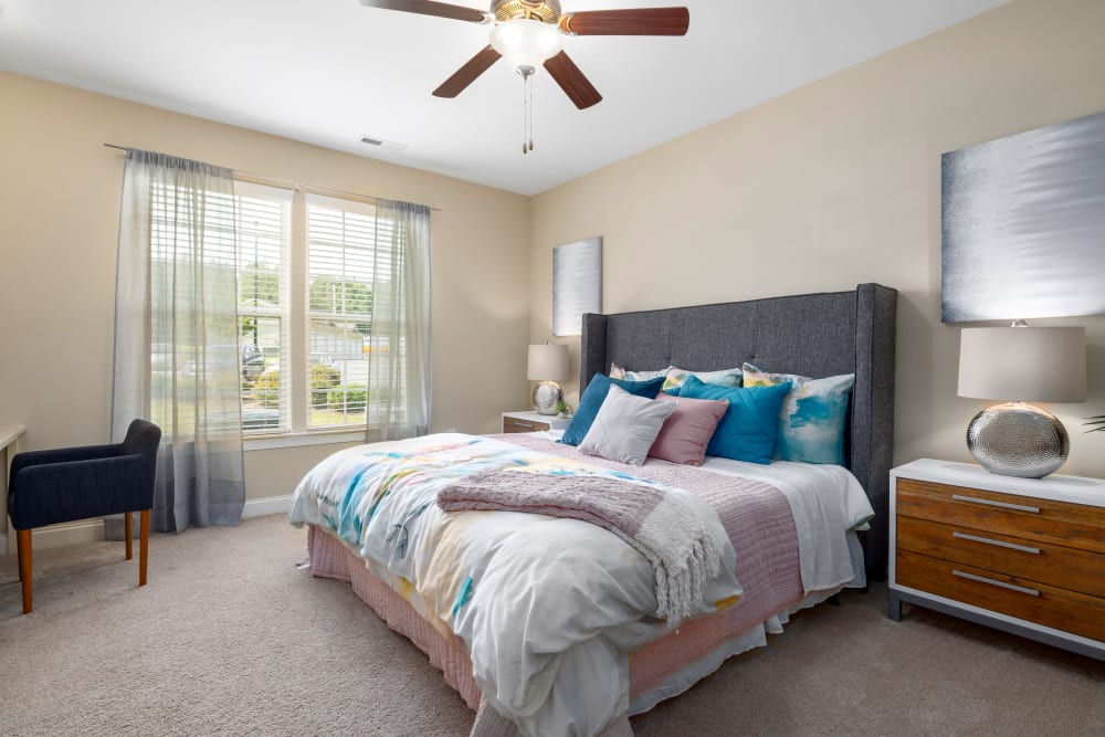 Model bedroom with blue accents looking towards a view at Marquis Ellis Crossing in Durham, North Carolina