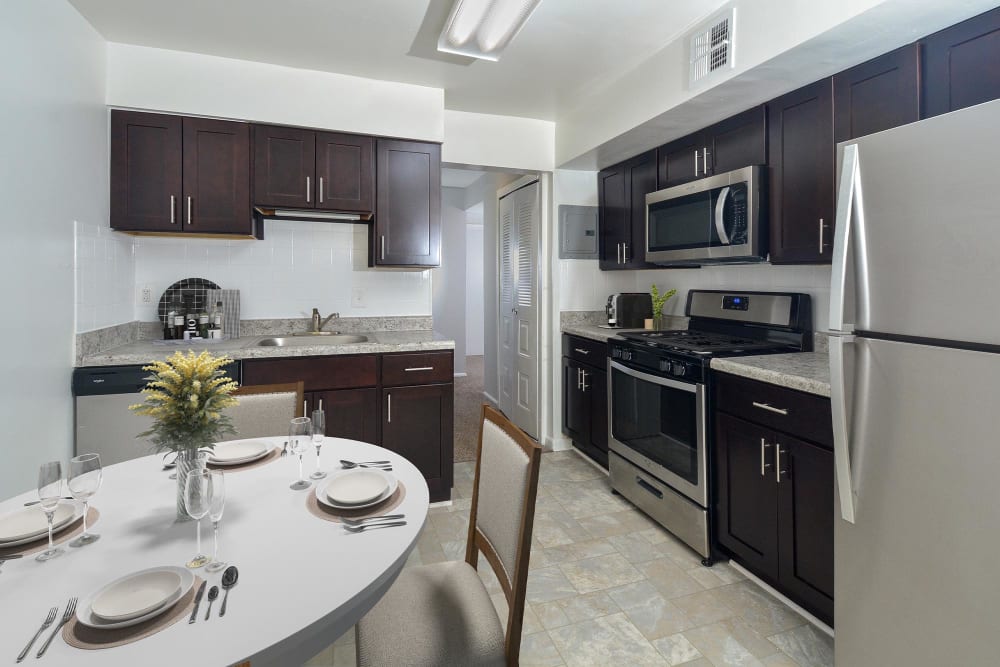 Modern eat-in kitchen with stainless-steel appliances and dark cabinetry at Landmark Glenmont Station in Silver Spring, Maryland