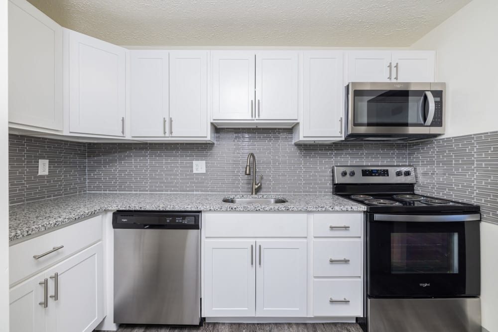 Updated kitchen with white cabinets, tile backsplash, and white appliances Westpointe Apartments in Pittsburgh, Pennsylvania